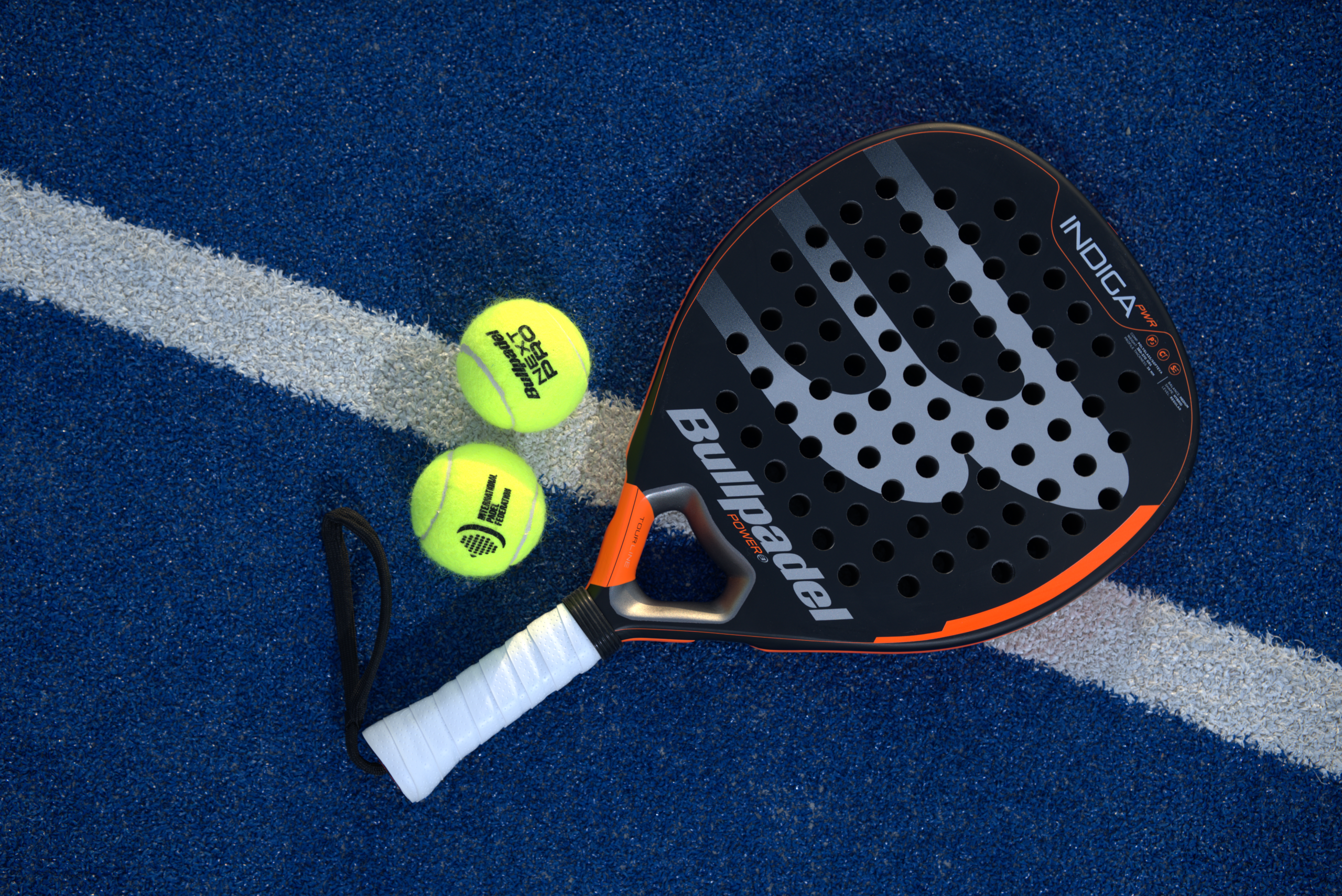 Padel Racket with premium pro balls on an outdoor court at sunset